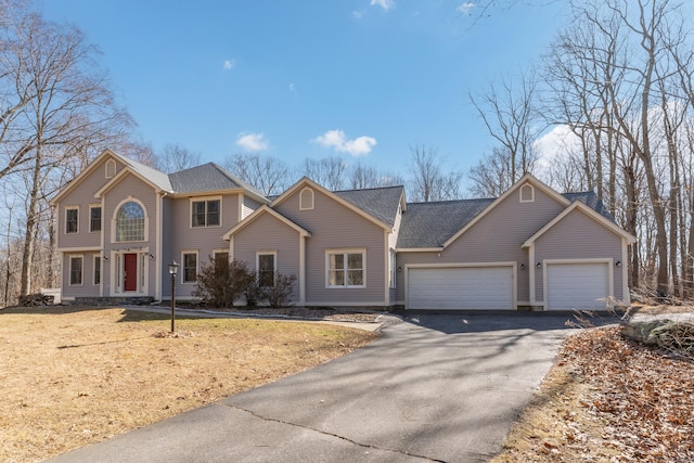 view of front facade featuring aphalt driveway, a front lawn, and an attached garage