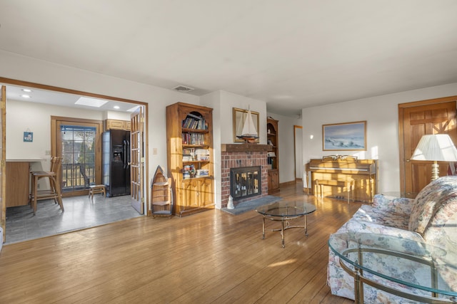 living room with recessed lighting, visible vents, a brick fireplace, and hardwood / wood-style floors