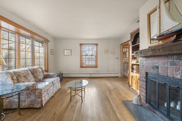 living area with visible vents, light wood-style flooring, a fireplace, and a baseboard radiator