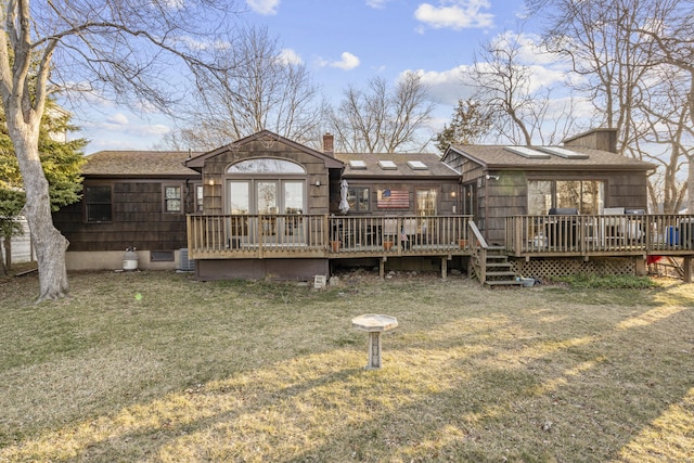 back of property with a yard, a deck, a chimney, and a shingled roof