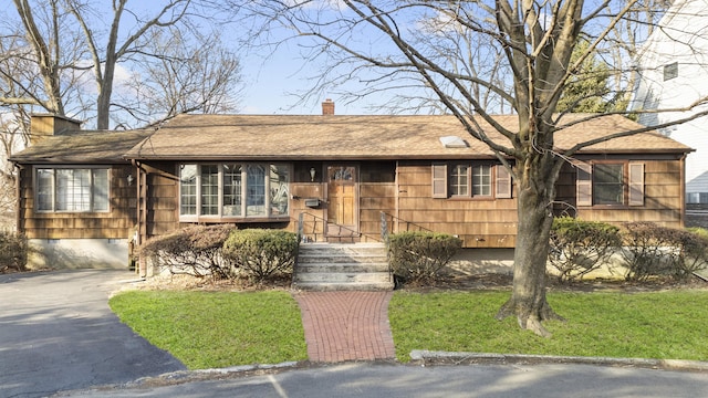 ranch-style home featuring roof with shingles and a chimney