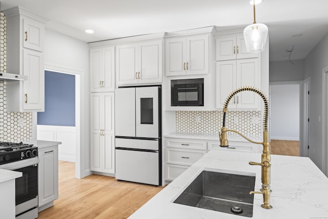 kitchen with range with gas cooktop, wall chimney exhaust hood, refrigerator with glass door, and white cabinetry