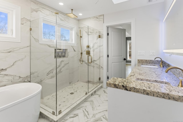 bathroom featuring marble finish floor, recessed lighting, a marble finish shower, a soaking tub, and vanity