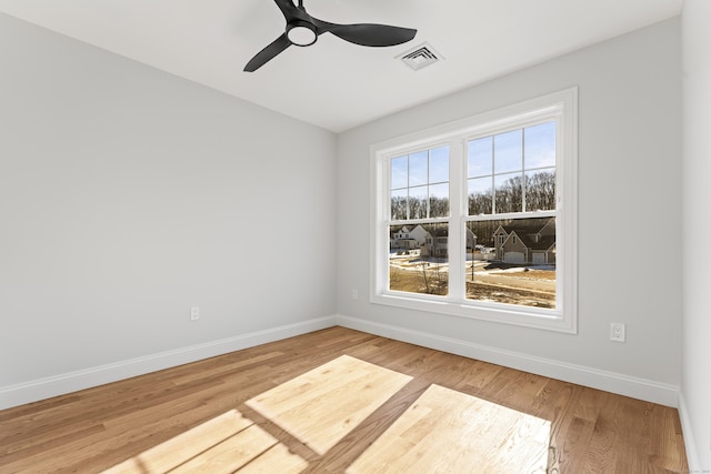 unfurnished room with visible vents, baseboards, wood finished floors, and a ceiling fan