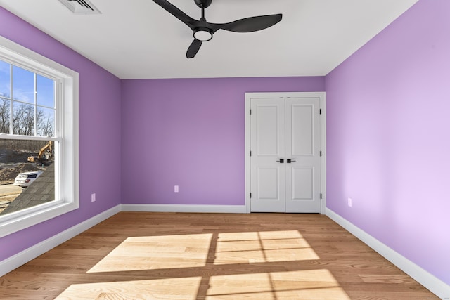 unfurnished bedroom featuring visible vents, baseboards, wood finished floors, a closet, and a ceiling fan