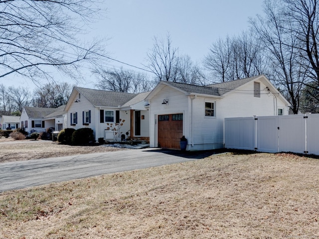 view of front of home with a shingled roof, fence, aphalt driveway, an attached garage, and a gate