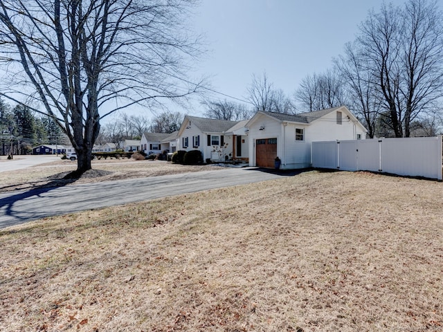 exterior space featuring a gate, driveway, an attached garage, and fence