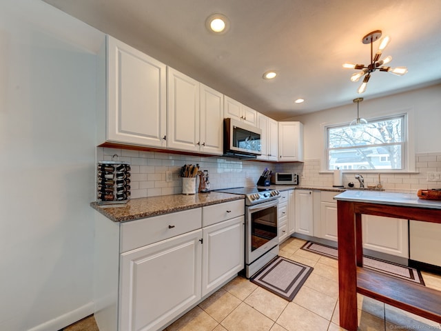 kitchen featuring light tile patterned floors, decorative backsplash, stainless steel appliances, a notable chandelier, and white cabinetry