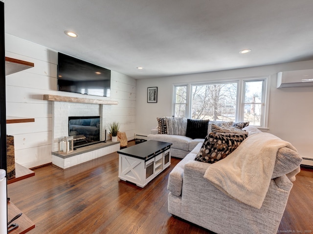 living room with dark wood finished floors, baseboard heating, recessed lighting, a fireplace, and a wall mounted AC