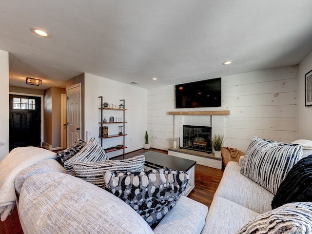 living room featuring wood finished floors, recessed lighting, wood walls, a fireplace, and baseboards