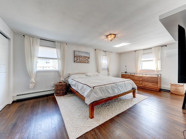 bedroom with multiple windows, baseboard heating, and hardwood / wood-style floors