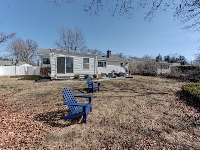 rear view of house with fence, a chimney, outdoor lounge area, a patio area, and a lawn