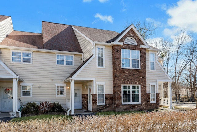 view of front facade with brick siding and roof with shingles