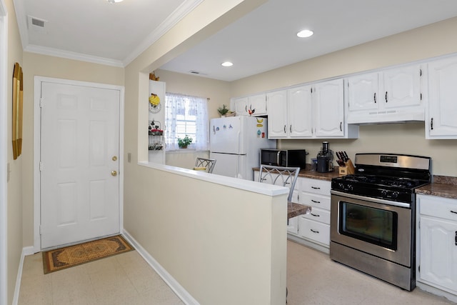 kitchen featuring stainless steel gas range oven, black microwave, under cabinet range hood, freestanding refrigerator, and white cabinets