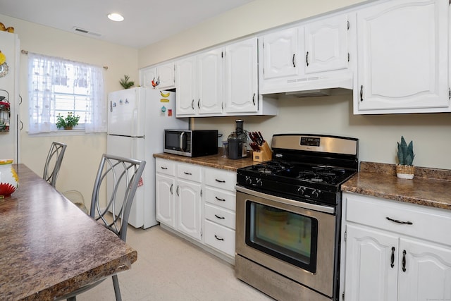 kitchen with under cabinet range hood, appliances with stainless steel finishes, white cabinetry, and dark countertops