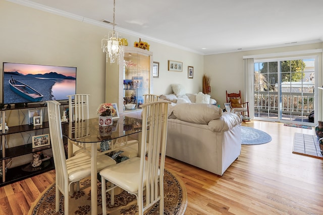 dining space with visible vents, an inviting chandelier, wood finished floors, and crown molding