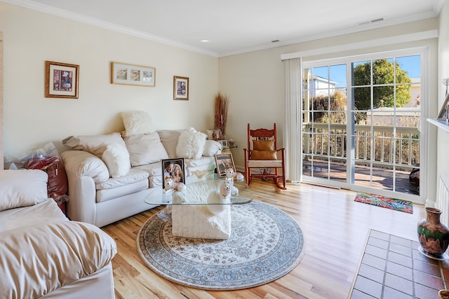 living area with visible vents, crown molding, and wood finished floors