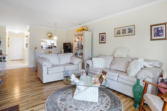 living room with a notable chandelier, crown molding, and light wood finished floors