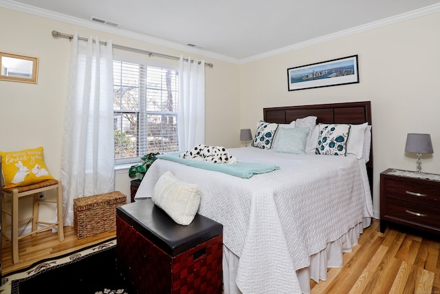 bedroom with light wood-type flooring, visible vents, and crown molding