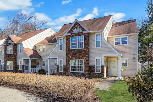 view of front facade featuring brick siding and a shingled roof