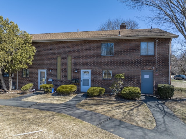 view of front of home with brick siding and a chimney