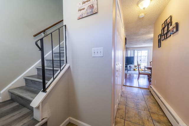 stairs with tile patterned flooring, baseboards, baseboard heating, and a textured ceiling