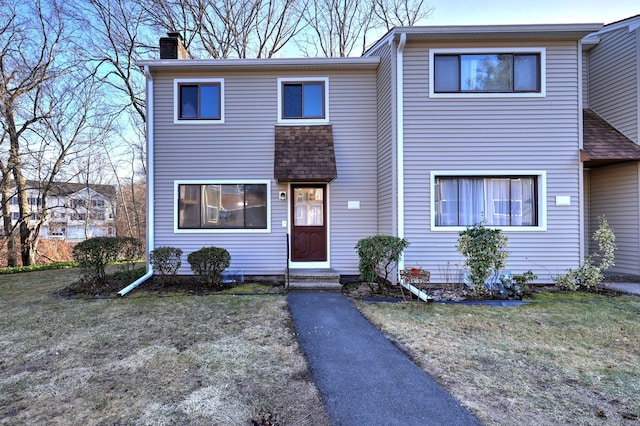 view of front of home with a front lawn, a chimney, and entry steps