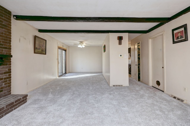 unfurnished living room featuring beamed ceiling, carpet floors, visible vents, and ceiling fan