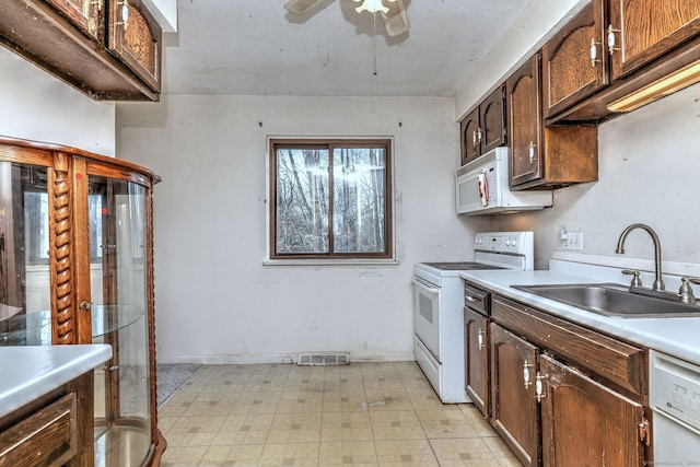 kitchen featuring white appliances, light floors, ceiling fan, a sink, and light countertops