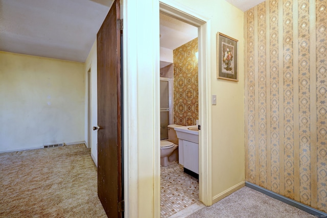 corridor with visible vents, light carpet, and baseboards