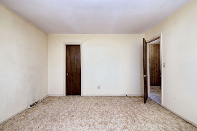 carpeted spare room featuring baseboards and visible vents