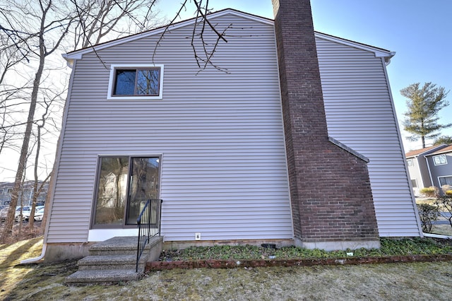 rear view of property featuring entry steps and a chimney