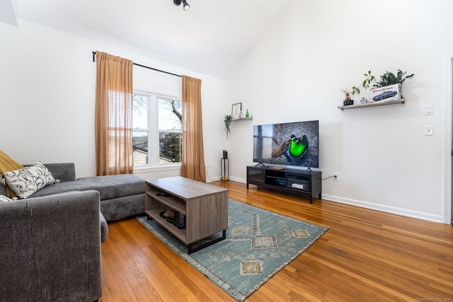 living room with lofted ceiling, hardwood / wood-style flooring, and baseboards