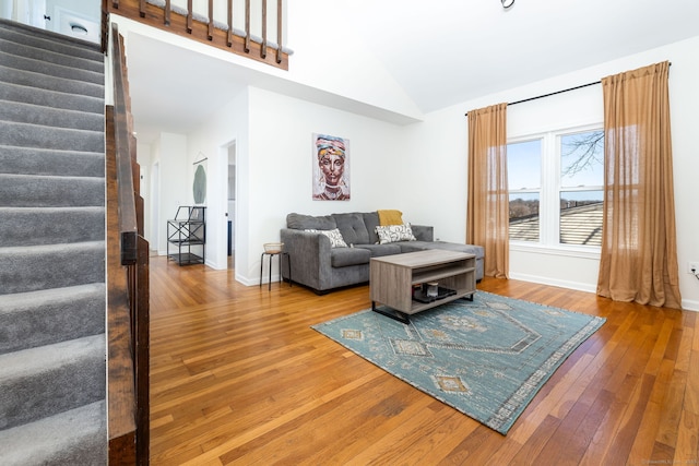 living room featuring baseboards, hardwood / wood-style floors, and stairs