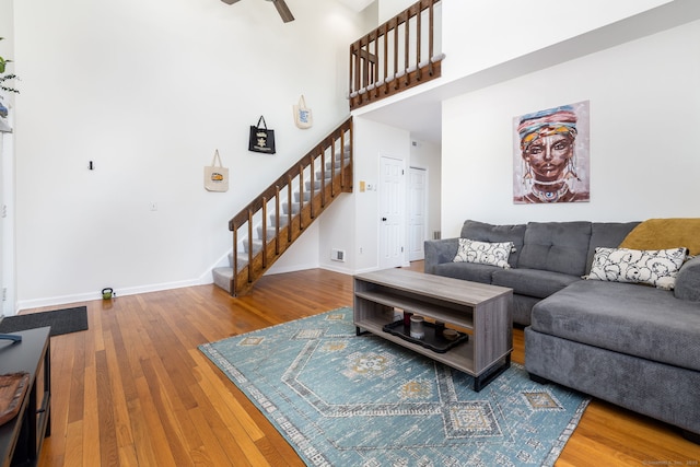 living room featuring hardwood / wood-style floors, a high ceiling, stairway, and baseboards