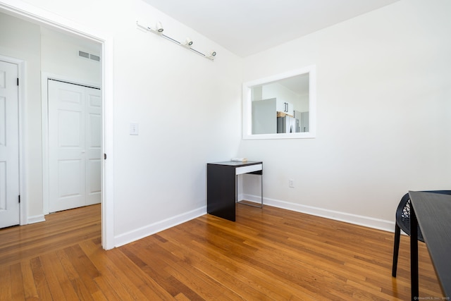 interior space with hardwood / wood-style floors, visible vents, and baseboards