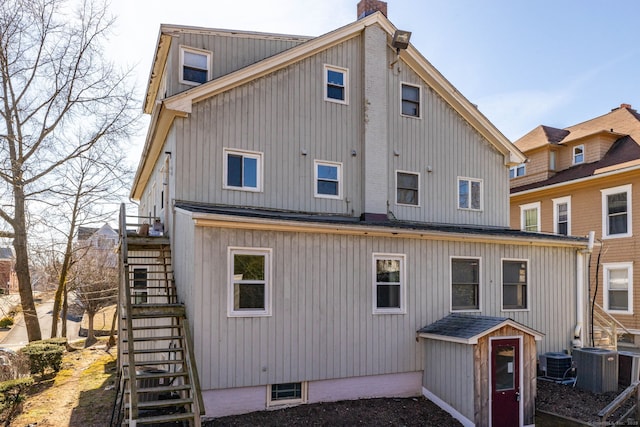 rear view of house with stairs, central AC, and a chimney