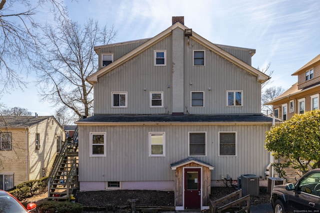 back of property with stairway and a chimney