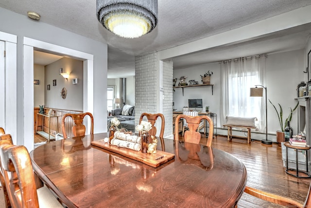 dining space with a baseboard radiator, a textured ceiling, and hardwood / wood-style flooring