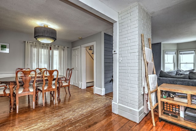 dining space with a baseboard radiator, baseboards, a textured ceiling, and hardwood / wood-style floors