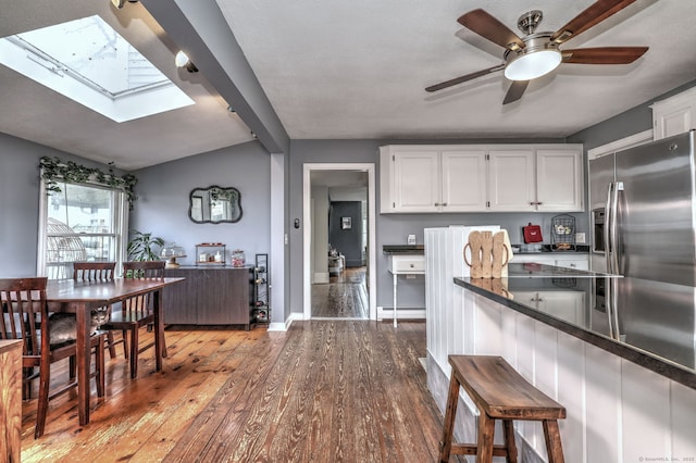 kitchen featuring dark countertops, white cabinets, a baseboard heating unit, and wood finished floors