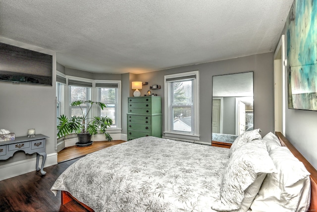 bedroom featuring dark wood-style floors, multiple windows, a textured ceiling, and baseboards