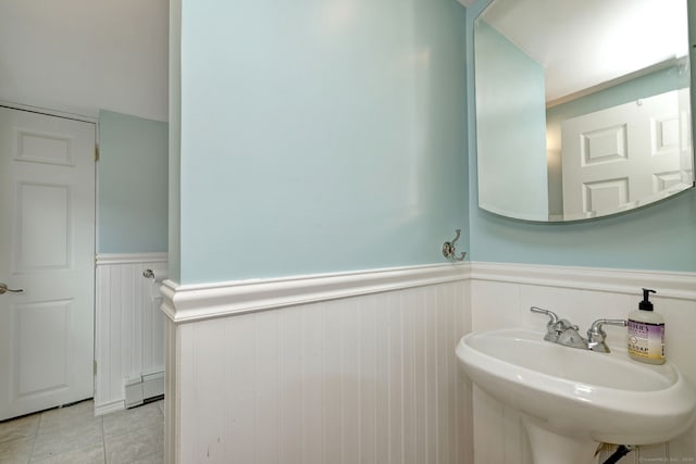 bathroom featuring a sink, a baseboard radiator, tile patterned flooring, and wainscoting