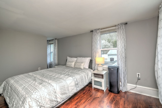 bedroom with dark wood finished floors and baseboards