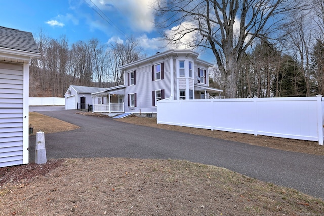 view of side of property with a garage, an outbuilding, driveway, and fence