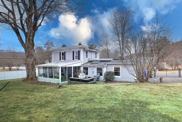 rear view of property featuring fence, a lawn, a sunroom, and a chimney