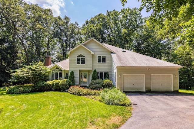 traditional home featuring a shingled roof, a front lawn, aphalt driveway, a chimney, and a garage