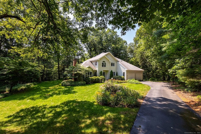 view of front of property with a garage, a chimney, and a front lawn