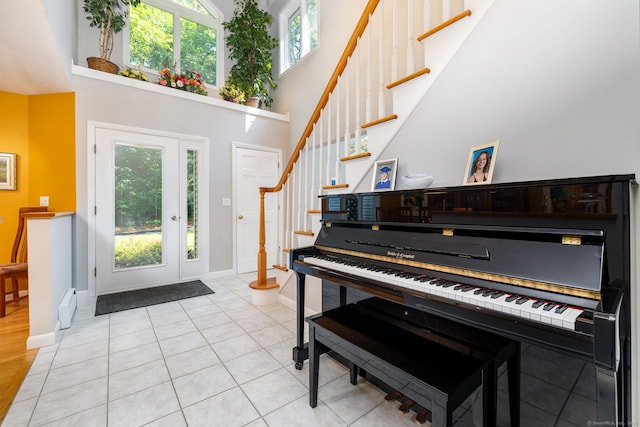 entrance foyer with a wealth of natural light, stairway, a towering ceiling, and light tile patterned floors