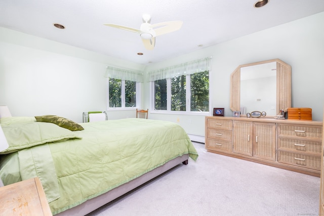 bedroom with light carpet, baseboard heating, and ceiling fan